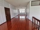 Long hallway with polished wooden floor and brown door