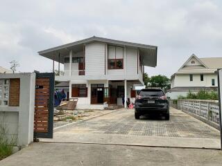 Front view of a modern two-story house with a driveway and parked car