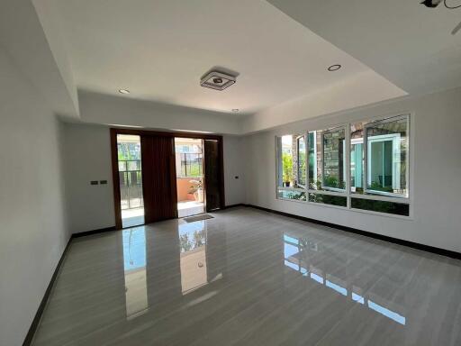 Spacious and well-lit living room with large windows and polished floors