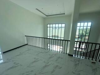 Spacious living area with large windows and a railings overlooking stairs