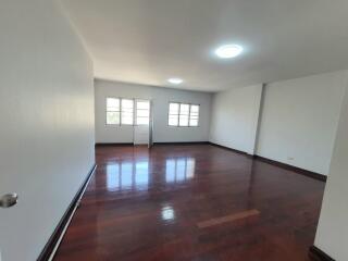 Spacious empty living room with wooden flooring and large windows