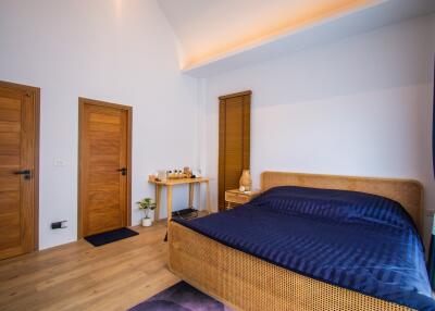 Modern bedroom with wooden doors, a bed, and a desk