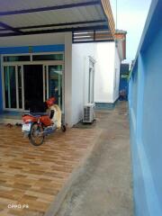 Exterior view of the property with a side pathway and a motorbike parked on the tiled yard