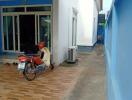 Exterior view of the property with a side pathway and a motorbike parked on the tiled yard