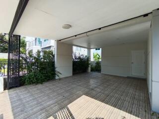 Covered carport with wooden flooring and garden view