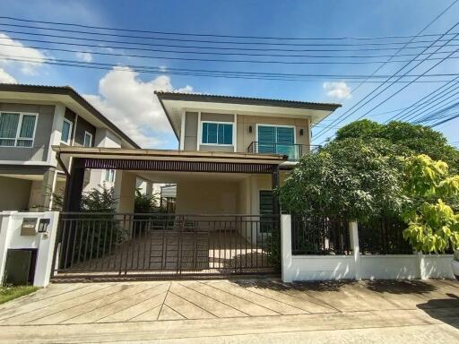 Exterior view of a modern two-story house with a gated driveway