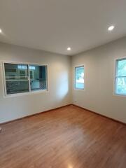 Empty room with wooden floor and two windows