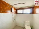 Bathroom with brown-tiled walls, white fixtures, and a water heater