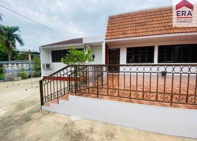 Exterior view of a one-story house with a tiled roof and a staircase leading to the entrance.