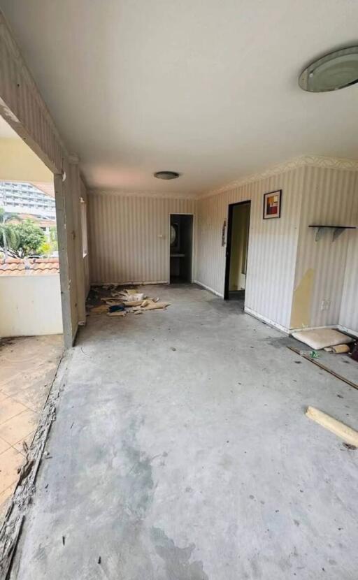 Living room with partially unfinished flooring and patterned wallpaper