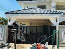 Front view of a residential house with a gated entrance and construction materials in the foreground