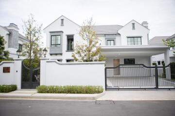 Front view of a modern house with a gated driveway and landscaped surroundings