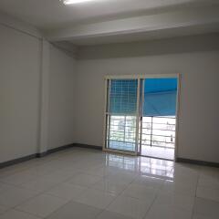 Spacious empty living room with tiled floor and access to a balcony