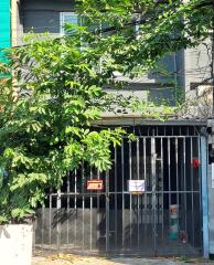 Front view of a building with gated entrance and leafy greenery