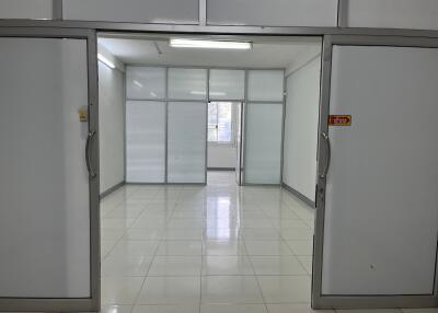 Empty office space with white tiled flooring and glass partitions