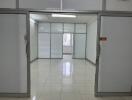 Empty office space with white tiled flooring and glass partitions