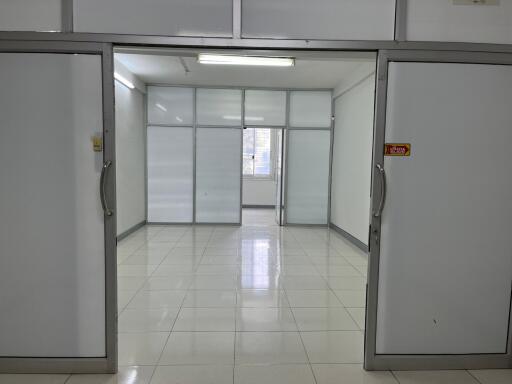 Empty office space with white tiled flooring and glass partitions