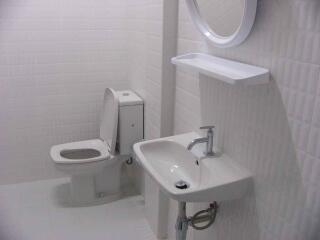 Clean and modern bathroom with white tiles, a toilet, and a sink