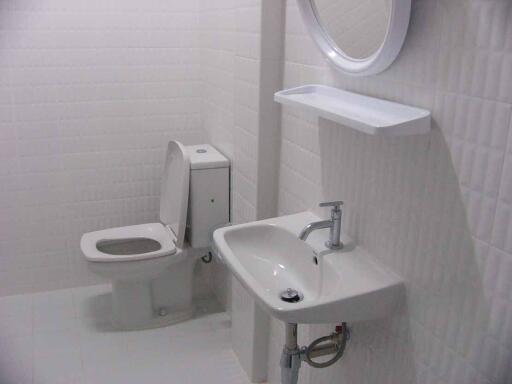 Clean and modern bathroom with white tiles, a toilet, and a sink