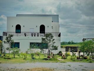 White two-story house with balcony and garden