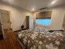 Comfortable bedroom with a double bed, wardrobe, window with blinds, air conditioning unit, and bedside table.
