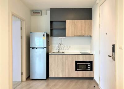 Modern kitchenette with wooden cabinets and steel appliances