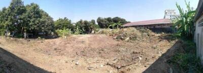 Cleared empty lot with surrounding trees and a nearby building