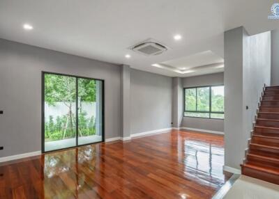 Spacious and modern living room with wooden floors, large windows, and a view of the garden