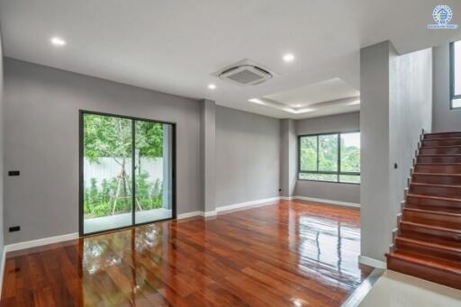 Spacious and modern living room with wooden floors, large windows, and a view of the garden