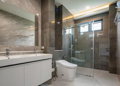 Modern bathroom with double sinks, a glass shower enclosure, and a large mirror