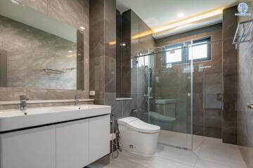 Modern bathroom with double sinks, a glass shower enclosure, and a large mirror