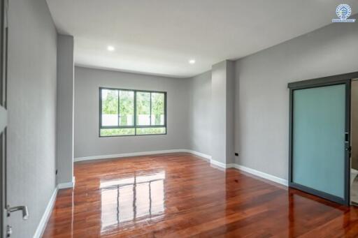 Spacious bedroom with large window and polished wooden floors