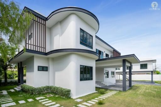 Modern two-story house exterior with large windows and well-maintained garden