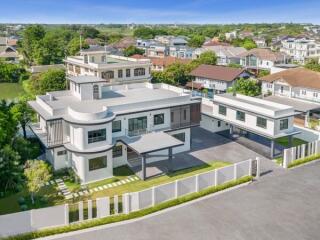 Spacious two-story white residential building with large windows and a landscaped yard