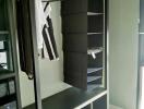 Open closet with hanging clothes and storage compartments