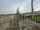 View of an empty lot with a gate and power lines