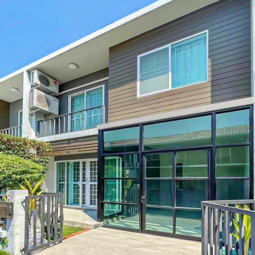 Modern two-story house exterior with large glass windows and a small garden