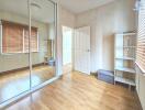 Bedroom with mirrored wardrobe and wooden flooring