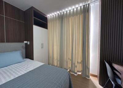 Well-lit modern bedroom with double bed, wardrobe, and study table