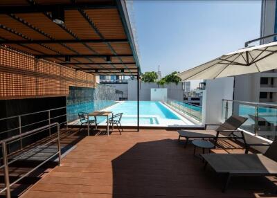 Rooftop pool area with lounge chairs and umbrella