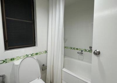 Modern bathroom with window, toilet, and bathtub-shower combination