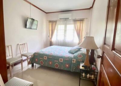 Bedroom with a bed, TV, and windows with curtains