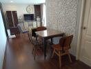 Dining area with a wooden floor, table, and chairs, adjacent to a living space with a TV