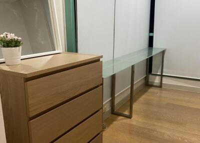 Bedroom with a wooden chest of drawers and glass-topped desk