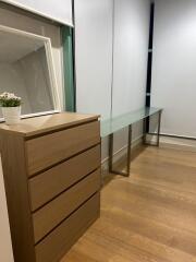 Bedroom with a wooden chest of drawers and glass-topped desk