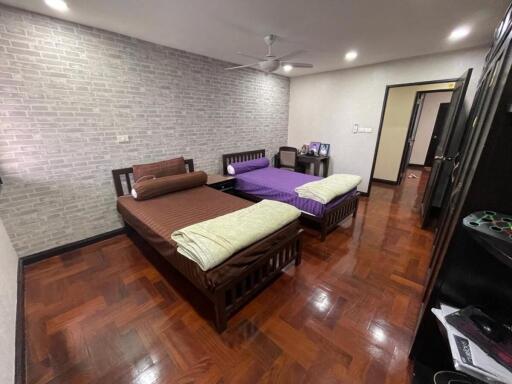 Spacious bedroom with two beds, wooden flooring, and a ceiling fan