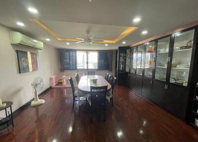 Spacious dining room with wooden floor, large dining table, display cabinet, and ceiling fan