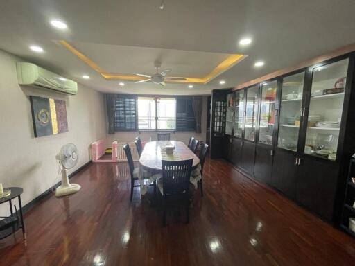 Spacious dining room with wooden floor, large dining table, display cabinet, and ceiling fan
