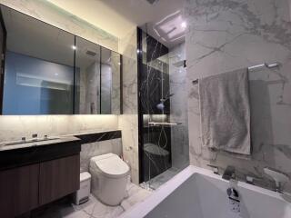 Modern bathroom with marble finishes, large mirror, and glass shower enclosure