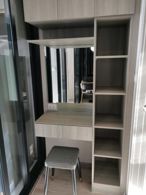 Well-organized vanity desk with a grey cushioned stool, shelves, and a mirror